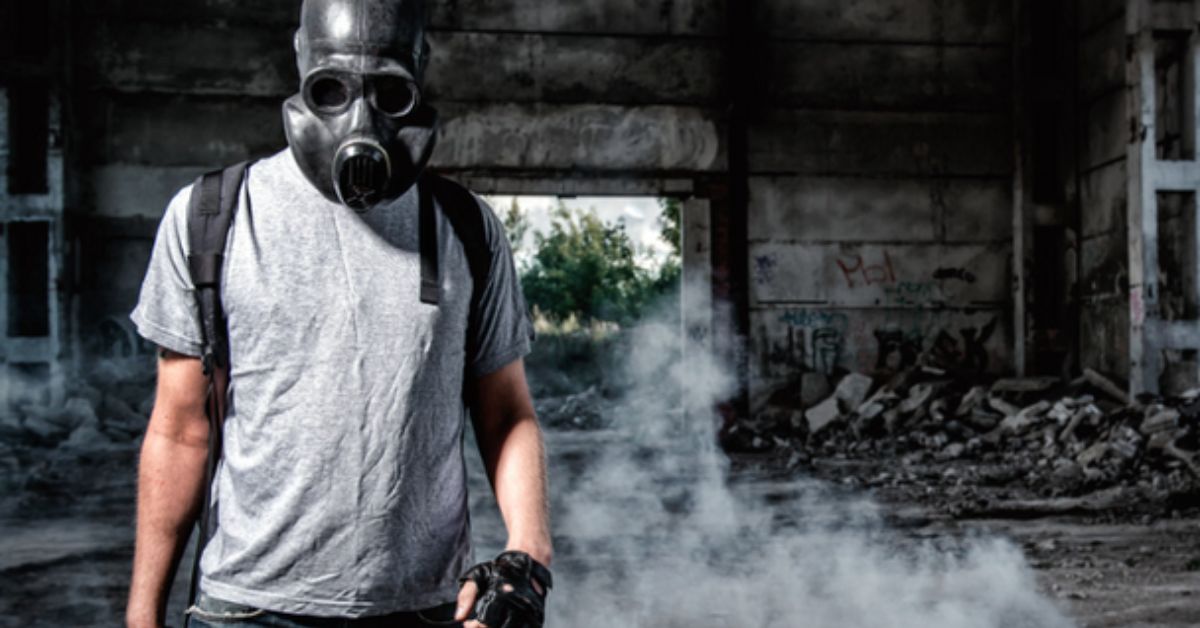 Man walking away from building wearing a gas mask.