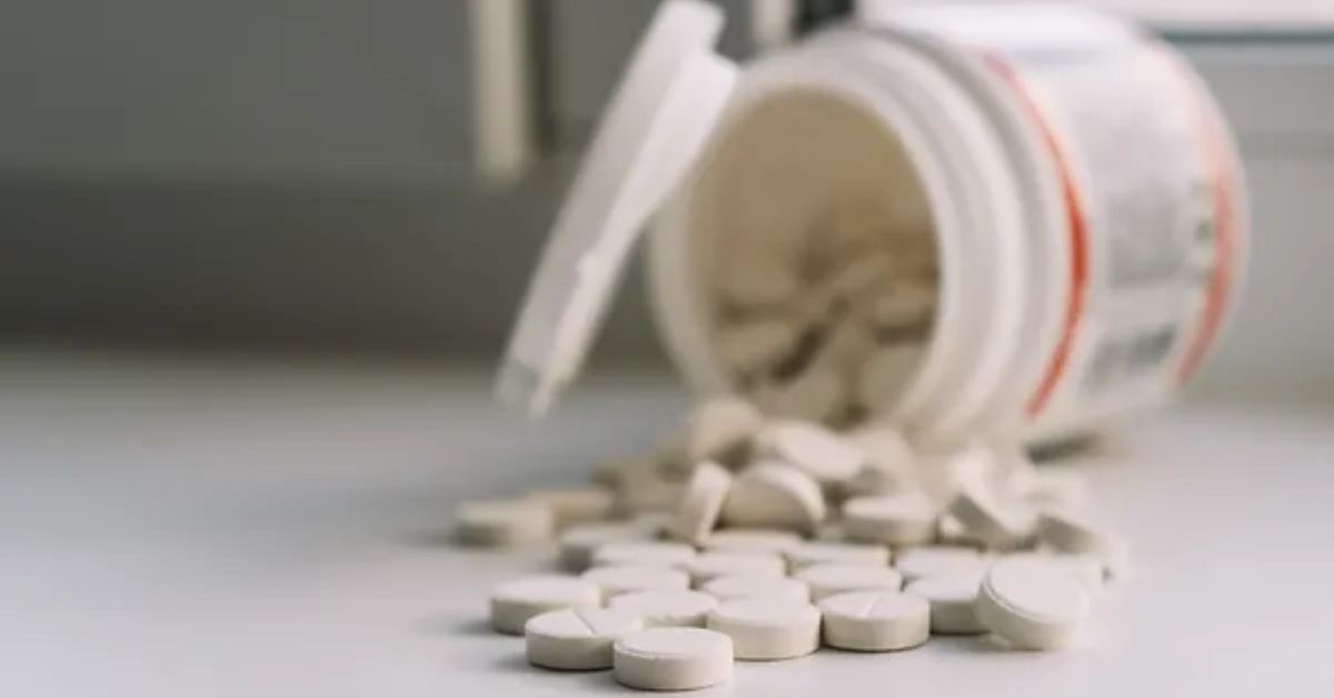 A bottle of pain pills laying on its side and pills that have fallen out.