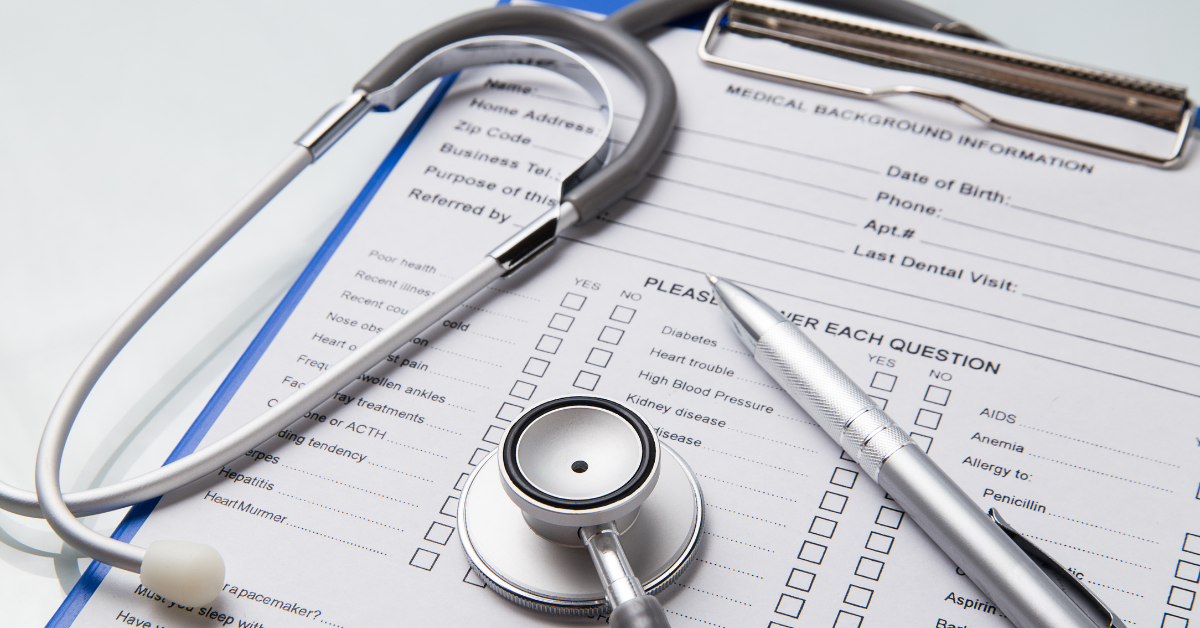 Medical intake form on a clipboard with stethoscope and pen resting on top